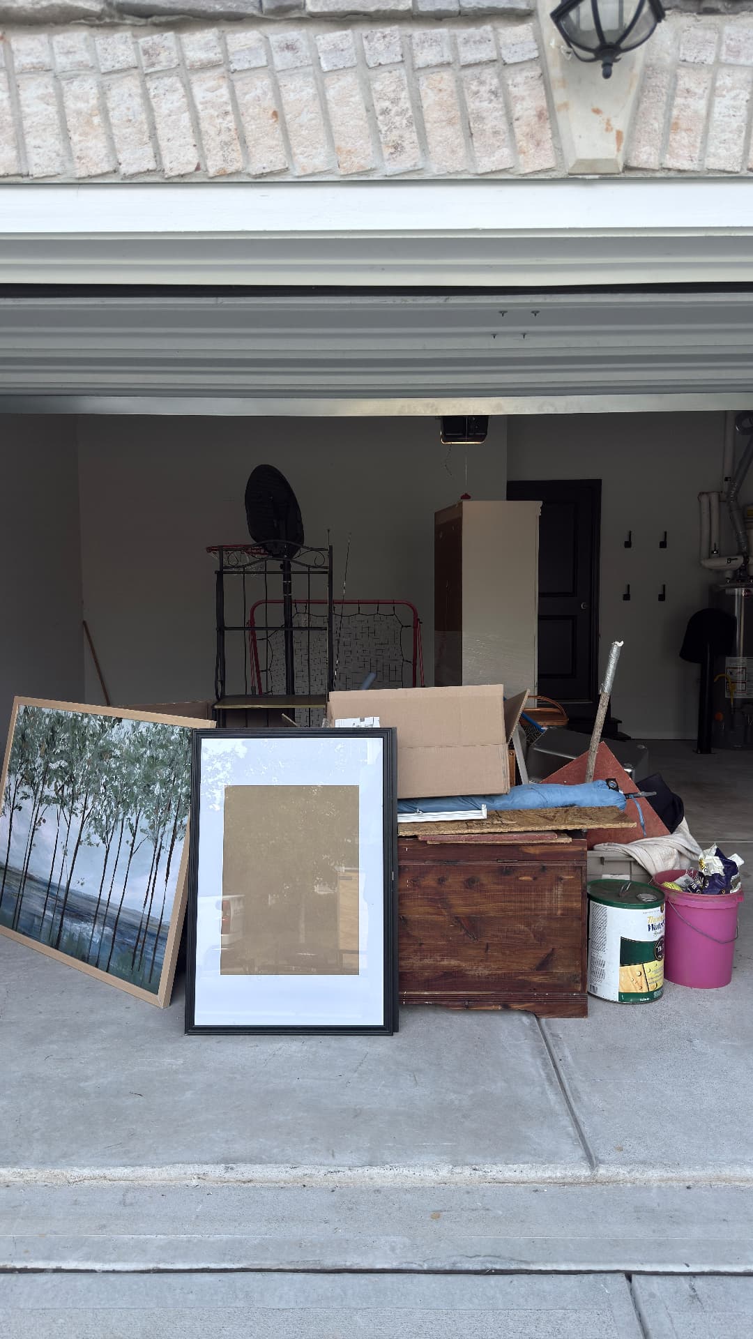 Garage before junk removal with furniture, boxes, frames, and household items ready to haul