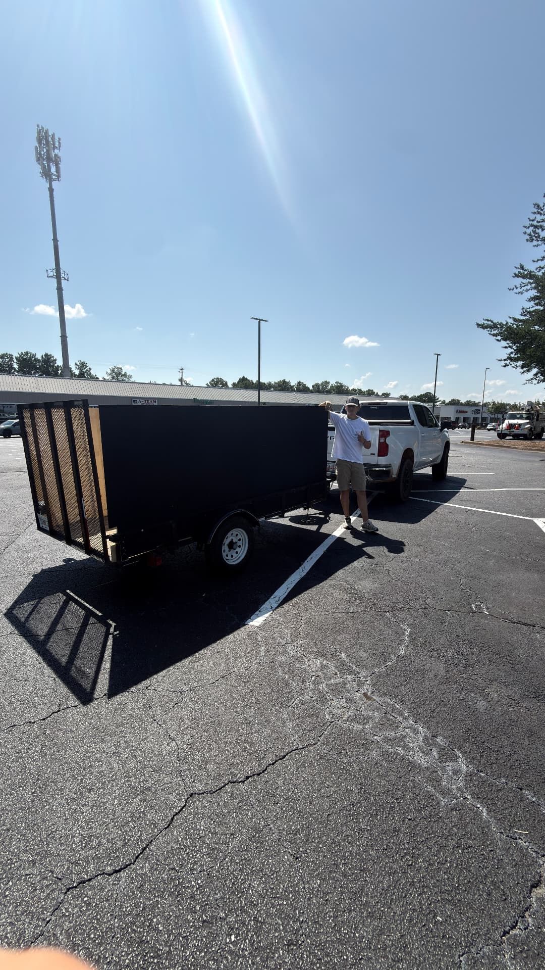 We Love Your Junk crew member standing beside a 5x10 dump trailer and pickup truck
