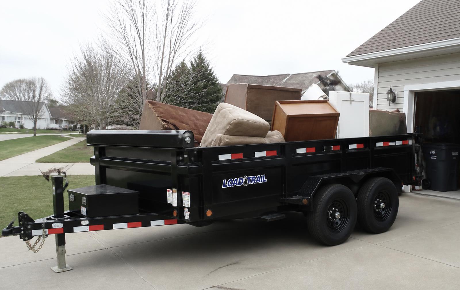 Loaded dump trailer parked in a driveway during a junk removal job